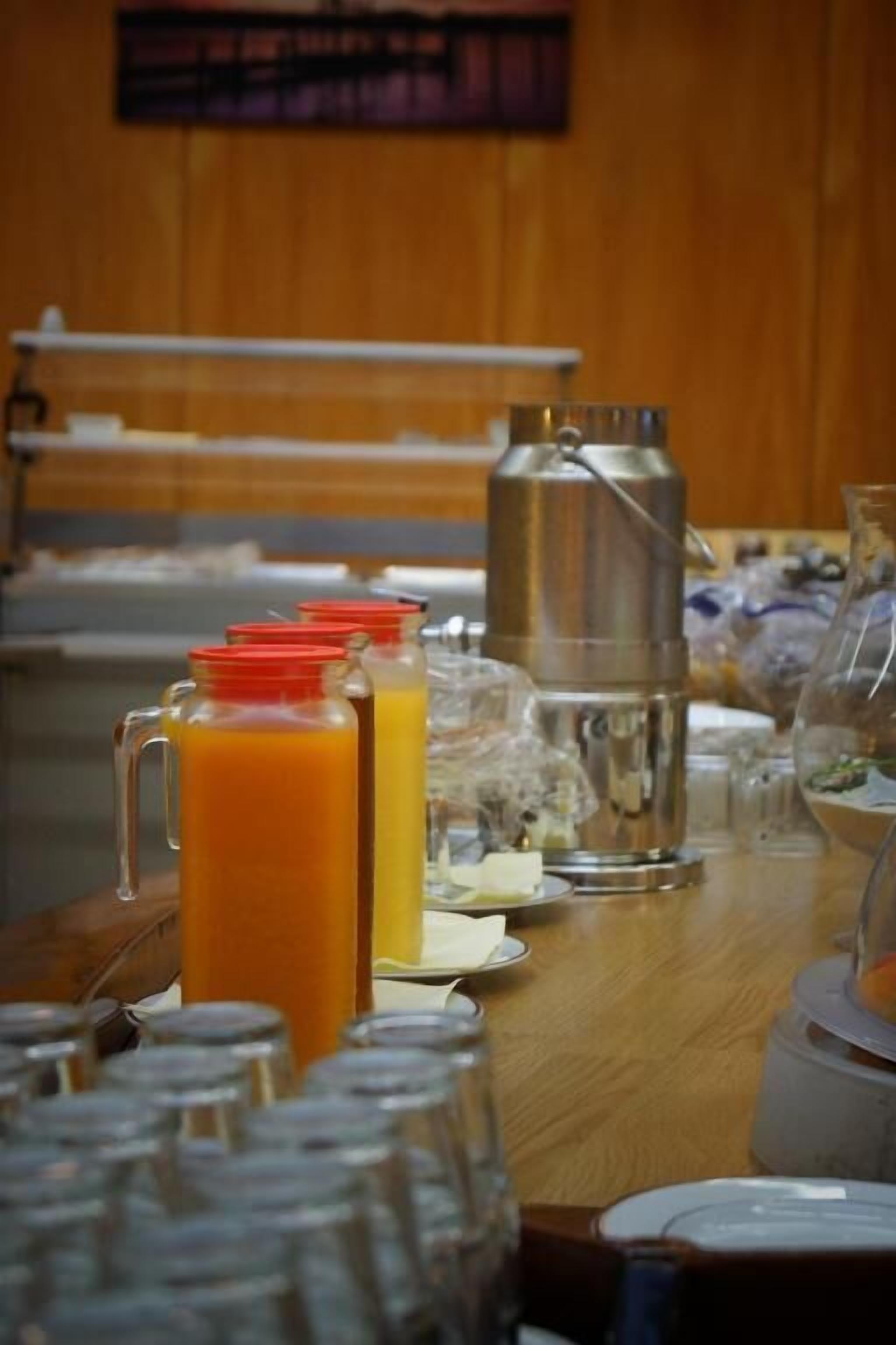 Ein Frühstückstisch mit Kaffeekanne, Orangensaftkaraffe und mehreren Gläsern.