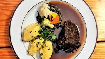 A plate with a piece of meat, mashed potatoes, and vegetables on a wooden table.
