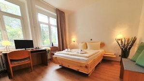 Une chambre à coucher avec un lit en bois, un bureau avec un ordinateur et de grandes fenêtres.