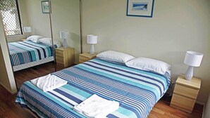 Ein Hotelzimmer mit zwei Betten, jeweils mit gestreifter Bettwäsche und weißen Kissen. An den Nachttischen stehen Lampen und ein gerahmtes Bild ist an der Wand zu sehen.