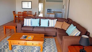 Ein Wohnzimmer mit braunem Sofa, gestreiftem Kissen, einem Holztisch und einer Lampe.