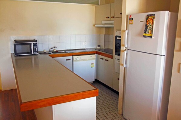 A compact kitchen with a microwave, sink, dishwasher, oven, and refrigerator.