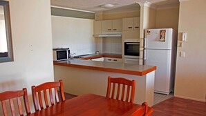 Eine kompakte Küche mit einer zentralen Kochinsel, einer Mikrowelle, einem Backofen und einem Kühlschrank.