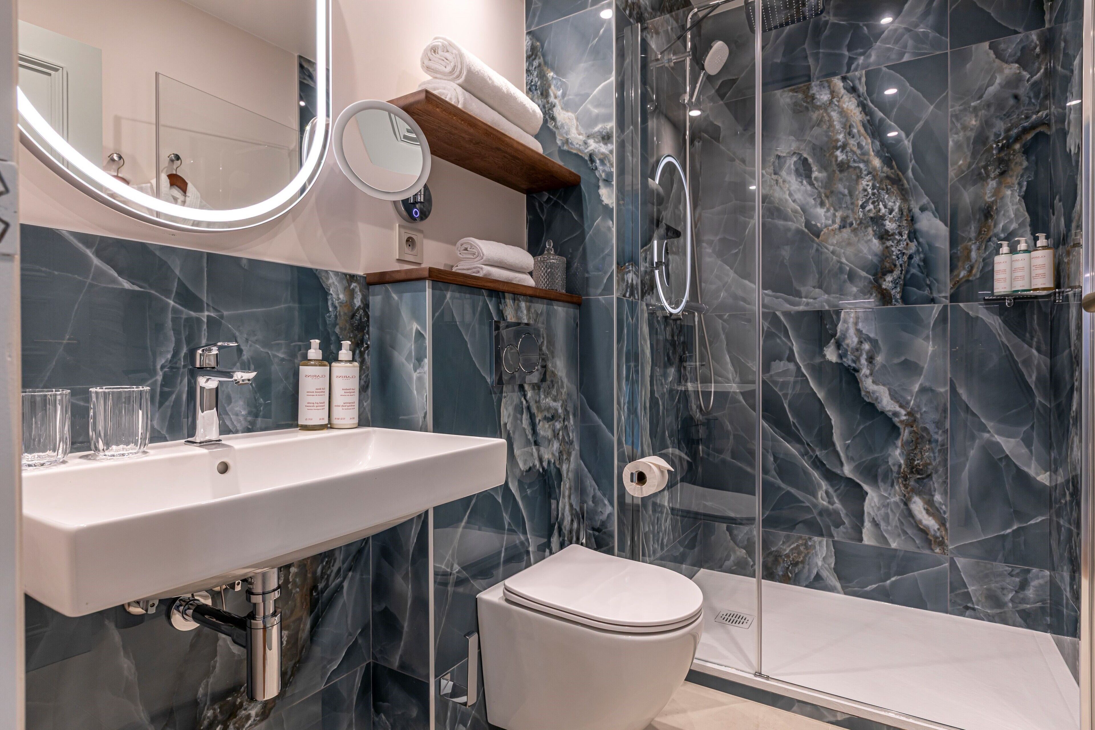 A modern bathroom with a marble sink, a toilet, and a glass-enclosed shower.