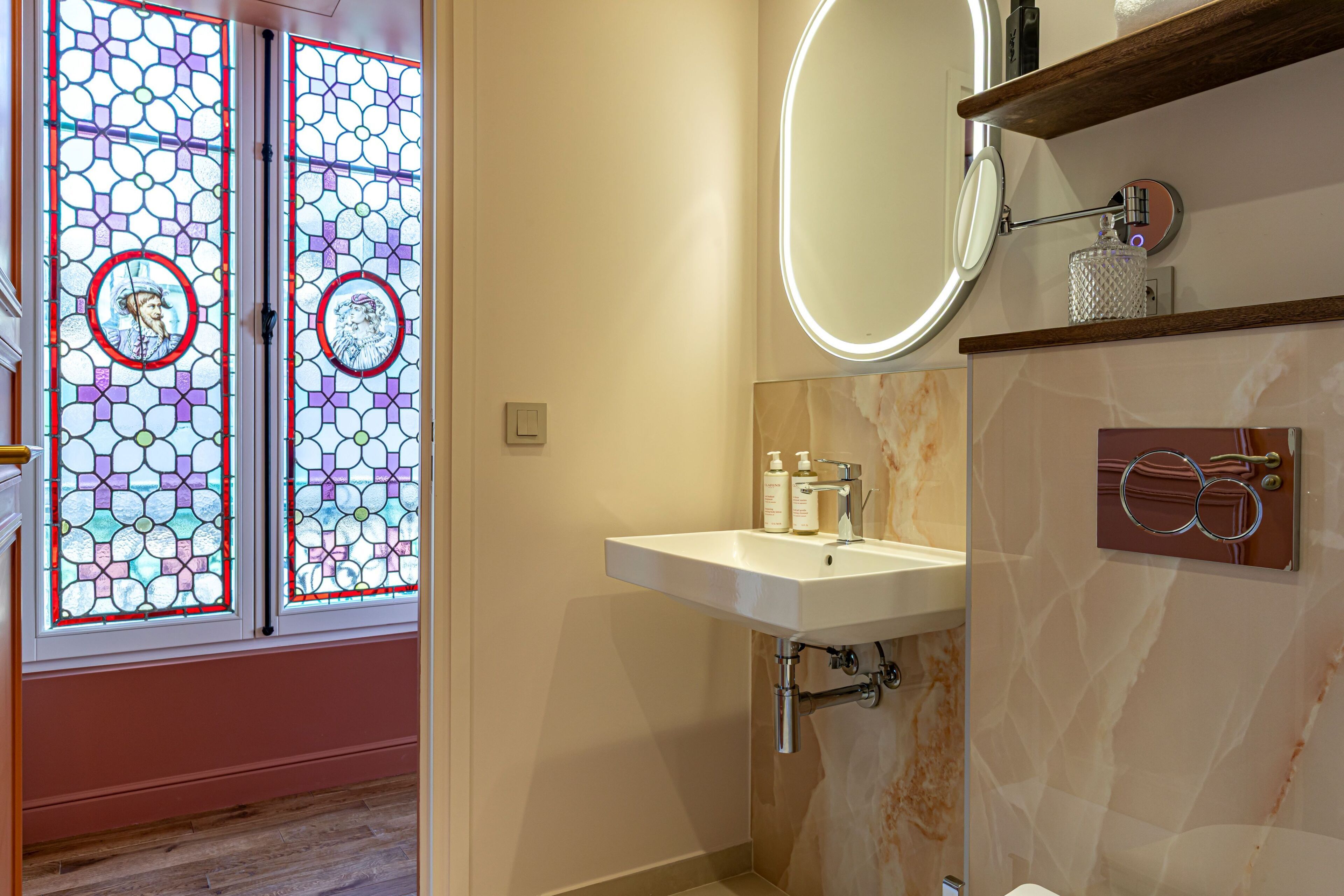 A bathroom with a white sink, a mirror, and a stained glass door.