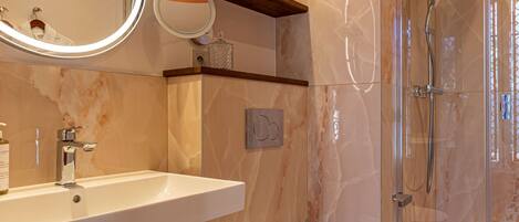 A modern bathroom with a sink, toilet, and glass-enclosed shower.
