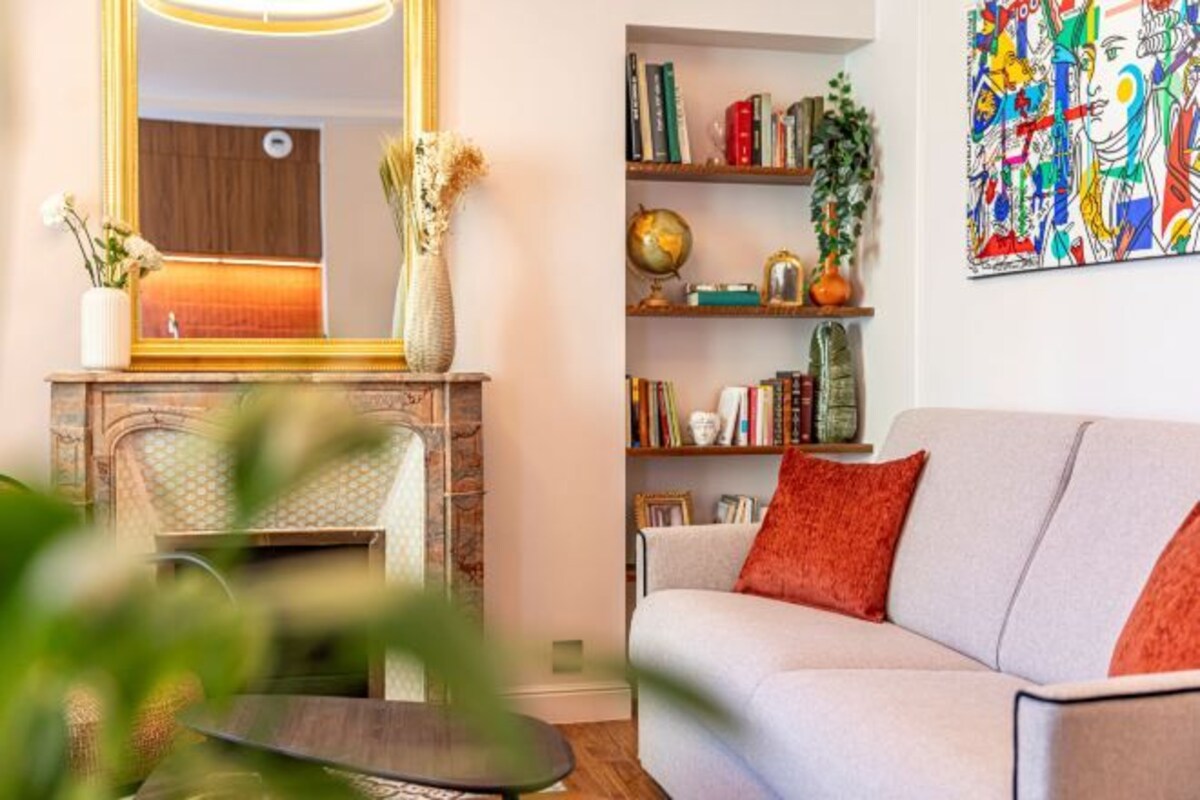 A living room with a fireplace, bookshelves, and a colorful abstract painting.