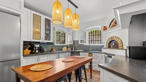 A modern kitchen with white cabinets, a wooden bar table, and a built-in oven. - Vacation home, 250 m from the beach (Théoule-sur-Mer)