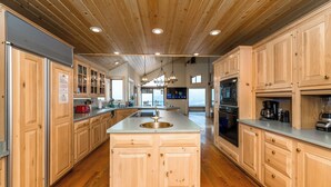 A spacious kitchen with wooden cabinets, a central island, and a large window providing a view of the outdoors. - MilkyWay_Lake Views! Air Conditioning, 3850SqFt, 3 Story, Game Room + HOA Amenities (Truckee)