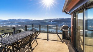 A balcony with a table and chairs, a grill, and a view of snow-covered mountains and a lake. - MilkyWay_Lake Views! Air Conditioning, 3850SqFt, 3 Story, Game Room + HOA Amenities (Truckee)