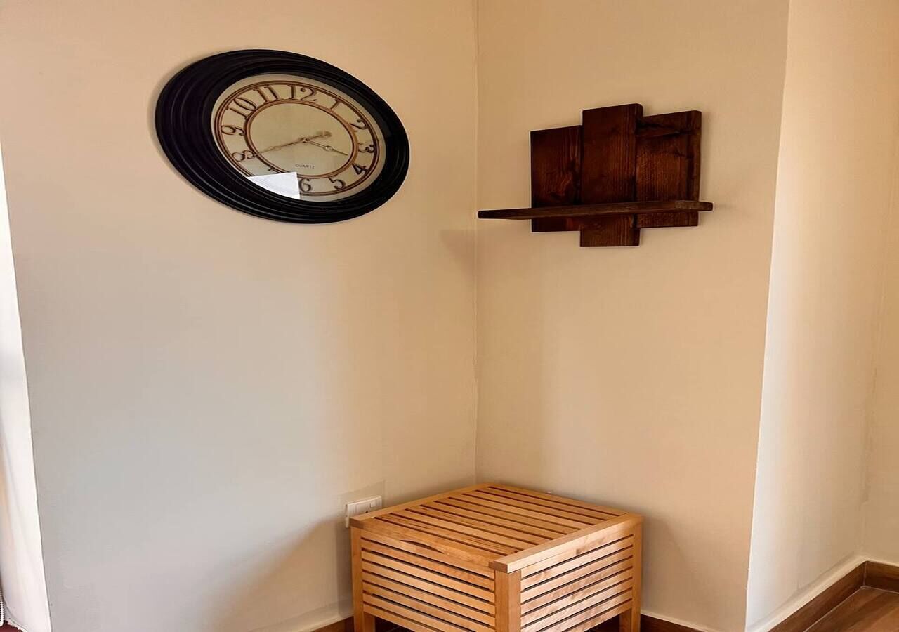 Een hoekzaal met een houten kast, een klok aan de muur en een houten bank.