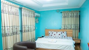 Ein Schlafzimmer mit Bett, Stuhl, Nachttisch und Vorhängen.