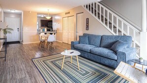 Ein Wohnzimmer mit einem blauen Sofa, einem Couchtisch und einem gemusterten Teppich.