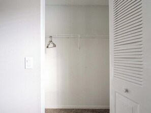 Ein Zimmer mit einer weißen Tür, einer weißen Wand und einer weißen Decke. Auf der rechten Seite befindet sich ein weißer Deckenlüfter.