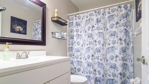 Ein Badezimmer mit Waschbecken, Spiegel, Toilette und einer Duschvorhang mit Elefantendruck.