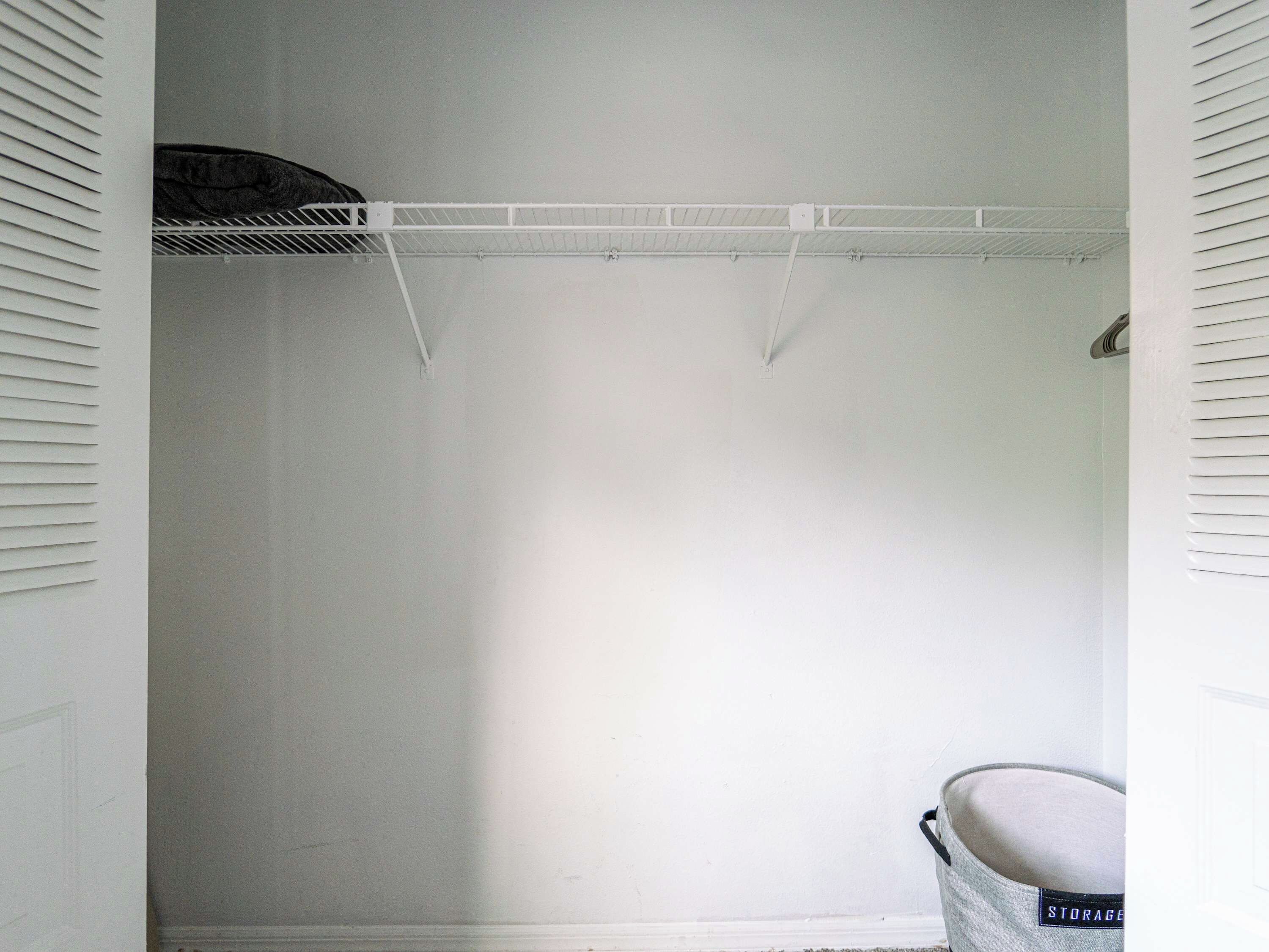 A white closet with a metal rod shelf and a hanging rod.