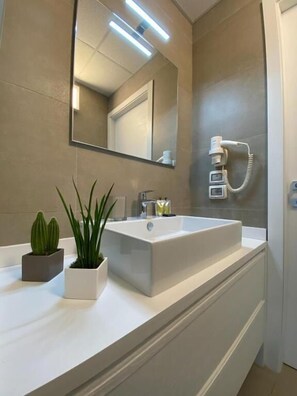 A modern bathroom with a large rectangular sink, a mirror, and a telephone. There are two potted plants on the vanity. - BEEAPARTMENTS  (Bari)