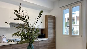 A modern kitchen with a white countertop, a green vase with plants, and a window with a view of buildings. - BEEAPARTMENTS  (Bari)
