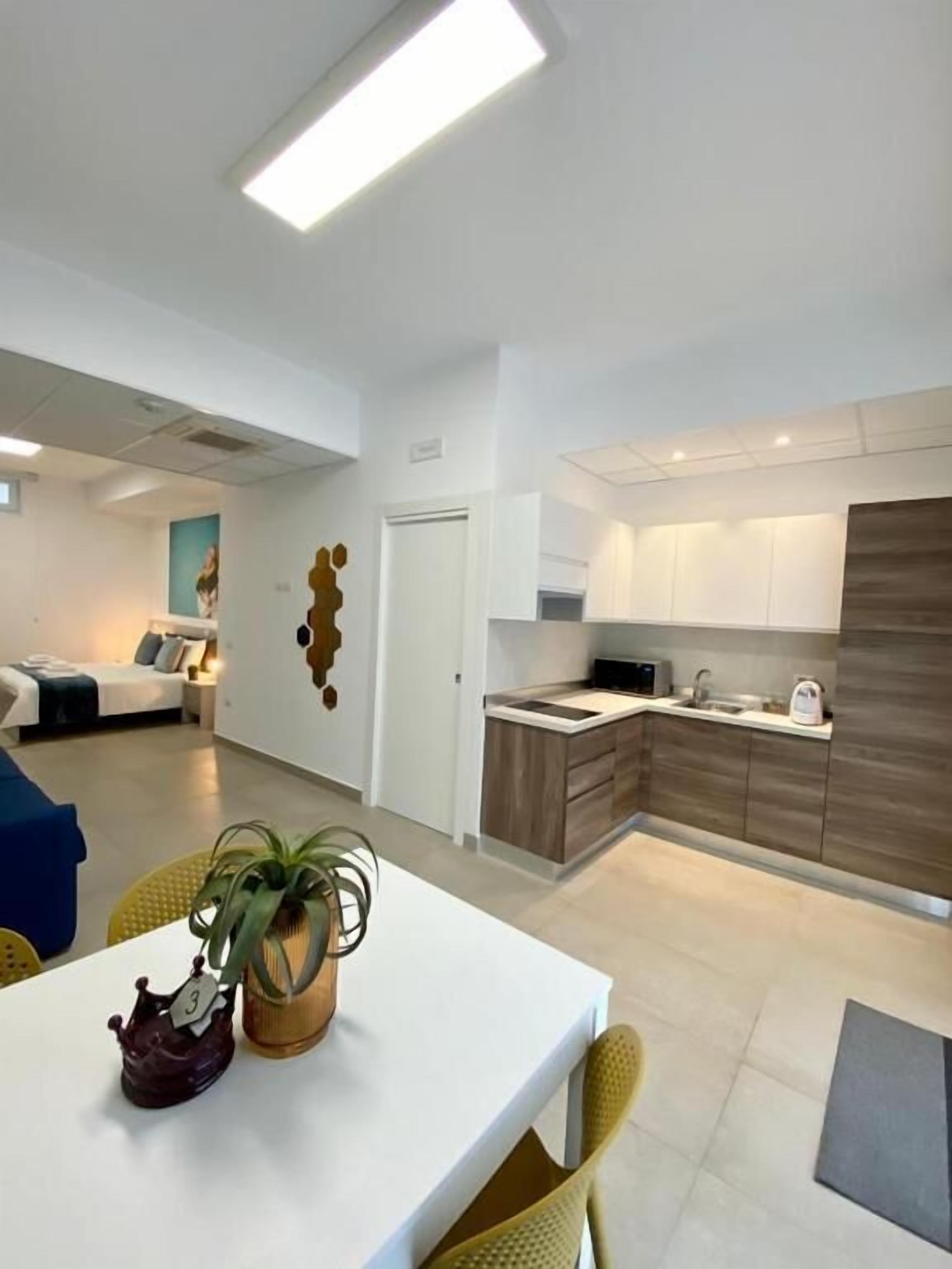 A modern apartment with a kitchen, dining area, and a bedroom.