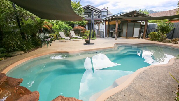 A swimming pool with lounge chairs and a covered patio area.