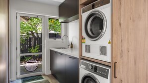 A compact laundry room with a washing machine, dryer, and sink.