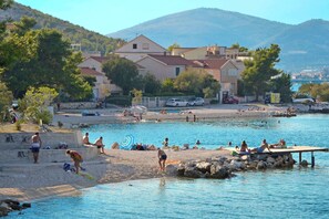 A coastal area with a swimming pool, beach, and buildings in the background. - Stylish studio Arya 1 - w/ sea view, 150m to beach (Mastrinka)