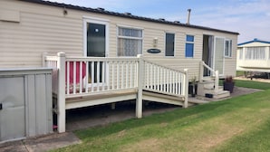 A mobile home with a porch, a small garden, and a neighboring trailer. - Chapel St Leonards Happydays Beachfield (Skegness)