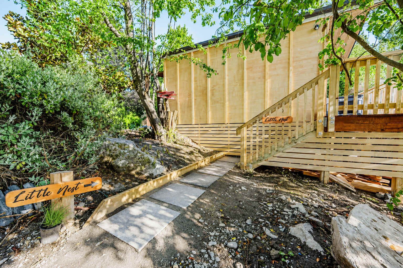 Une terrasse en bois avec un escalier menant à une structure en bois portant l’inscription « Petit Nid ».