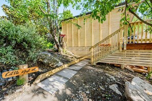 Eine Holzterrasse mit einer Treppe zu einer Holzhütte mit der Aufschrift 'Little Nest'.