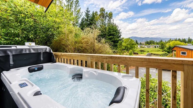 Ein Whirlpool auf einer Holzterrasse mit Blick auf einen Wald und Berge.