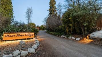 A sign for Ohana Tekapo Cottages with a gravel path leading to a building.