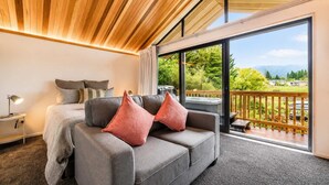 Ein modernes Schlafzimmer mit großem Fenster, einer Couch, einem Bett und einer Whirlwanne.