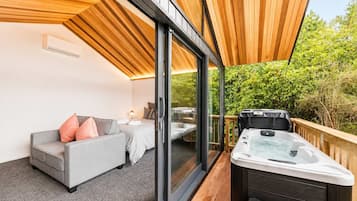 A modern outdoor living area with a sofa, a table, and a hot tub.