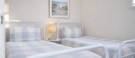 A bedroom with two beds, a bedside table with a lamp, and a framed picture on the wall.