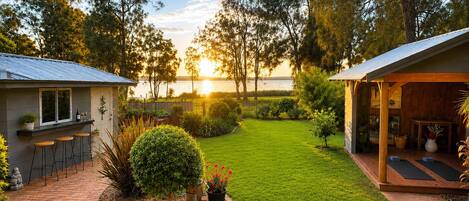 A well-maintained backyard with a barbecue area, a covered seating space, and a view of the water.