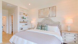 A bedroom with a large bed, bedside tables, a wardrobe, and a painting on the wall. - SunKissed @ St. George Island (Eastpoint)
