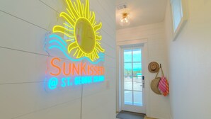 A hallway with a neon sign reading "Sunkissed" and a sun graphic. - SunKissed @ St. George Island (Eastpoint)