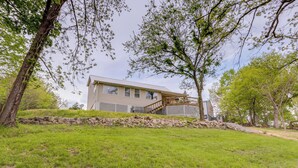 Une maison à deux étages dotée d’une terrasse en bois et d’un mur de soutènement en pierre.