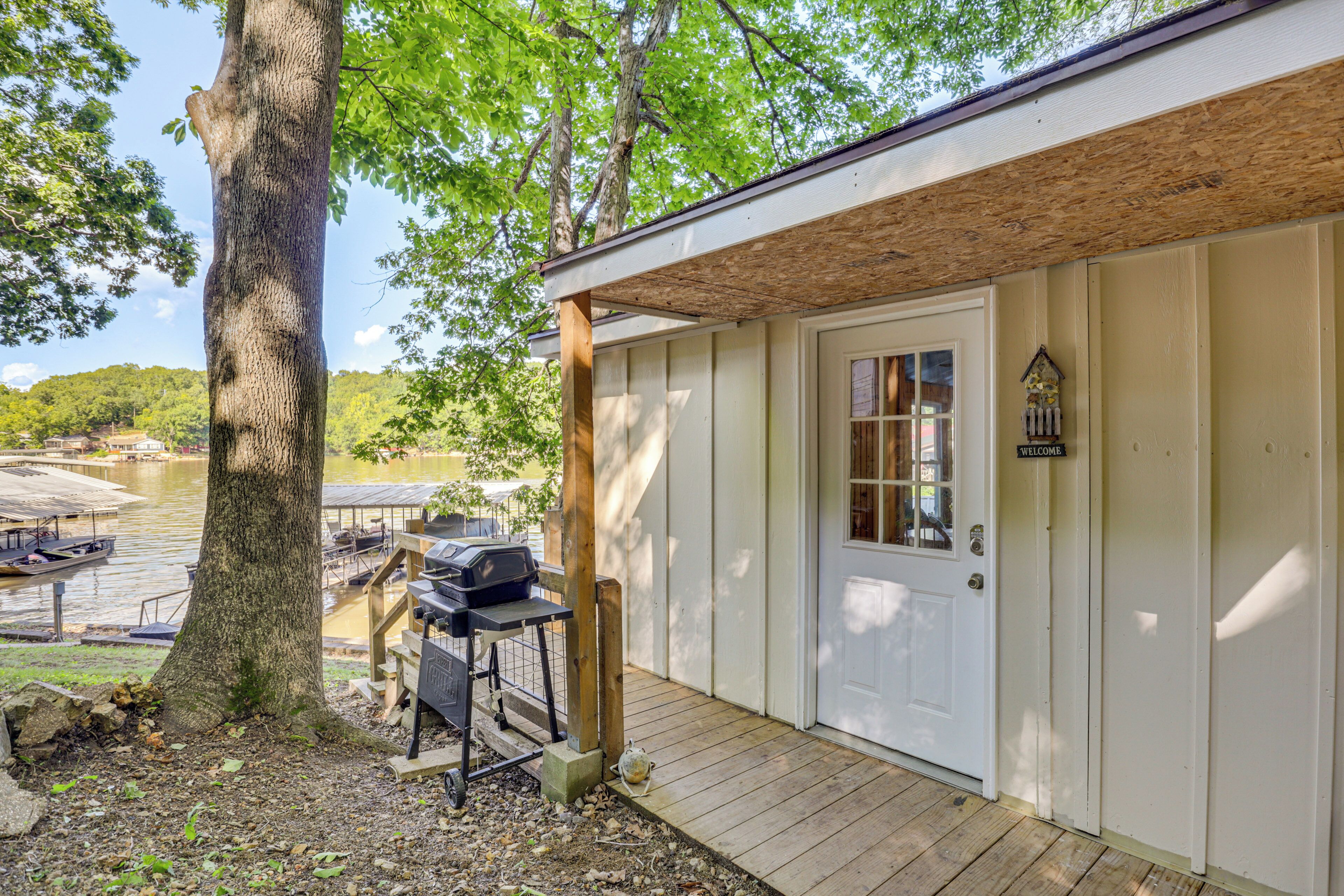 A wooden cabin with a porch, a grill, and a welcome sign.