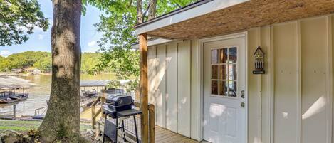 A wooden cabin with a porch, a grill, and a welcome sign.