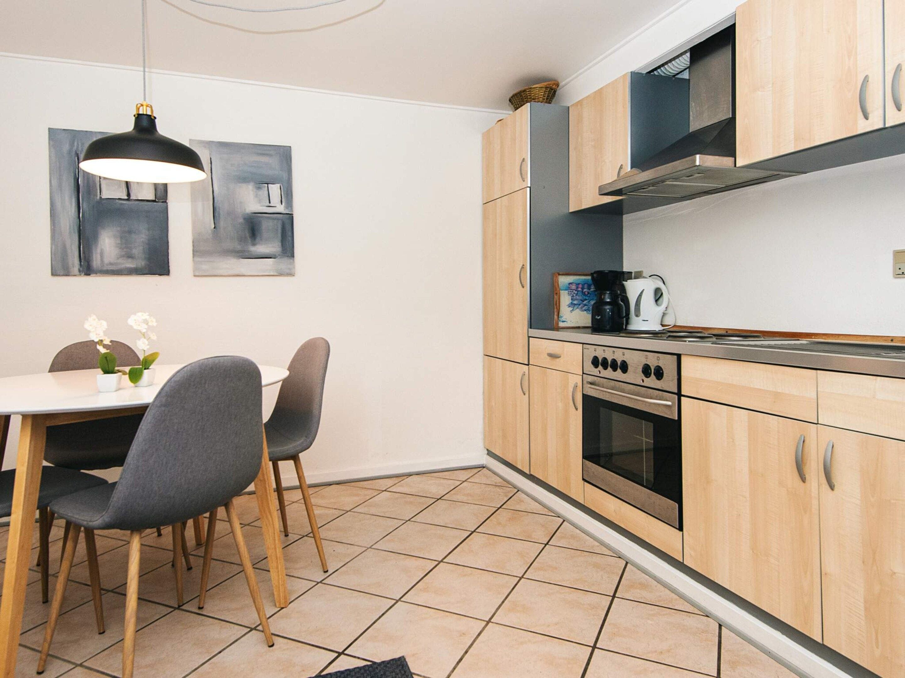 Una cocina moderna con armarios de madera, una estufa y un comedor con mesa y sillas.