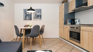 Una cocina compacta con armarios de madera, una mesa de comedor con sillas y una lámpara colgante.