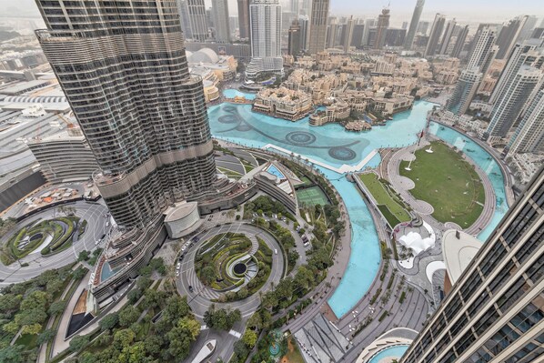 A high-rise building with a curved facade, a central landscaped area with a pool, and surrounding high-rise buildings.