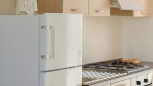Una cocina con un refrigerador blanco, una estufa y armarios de madera.