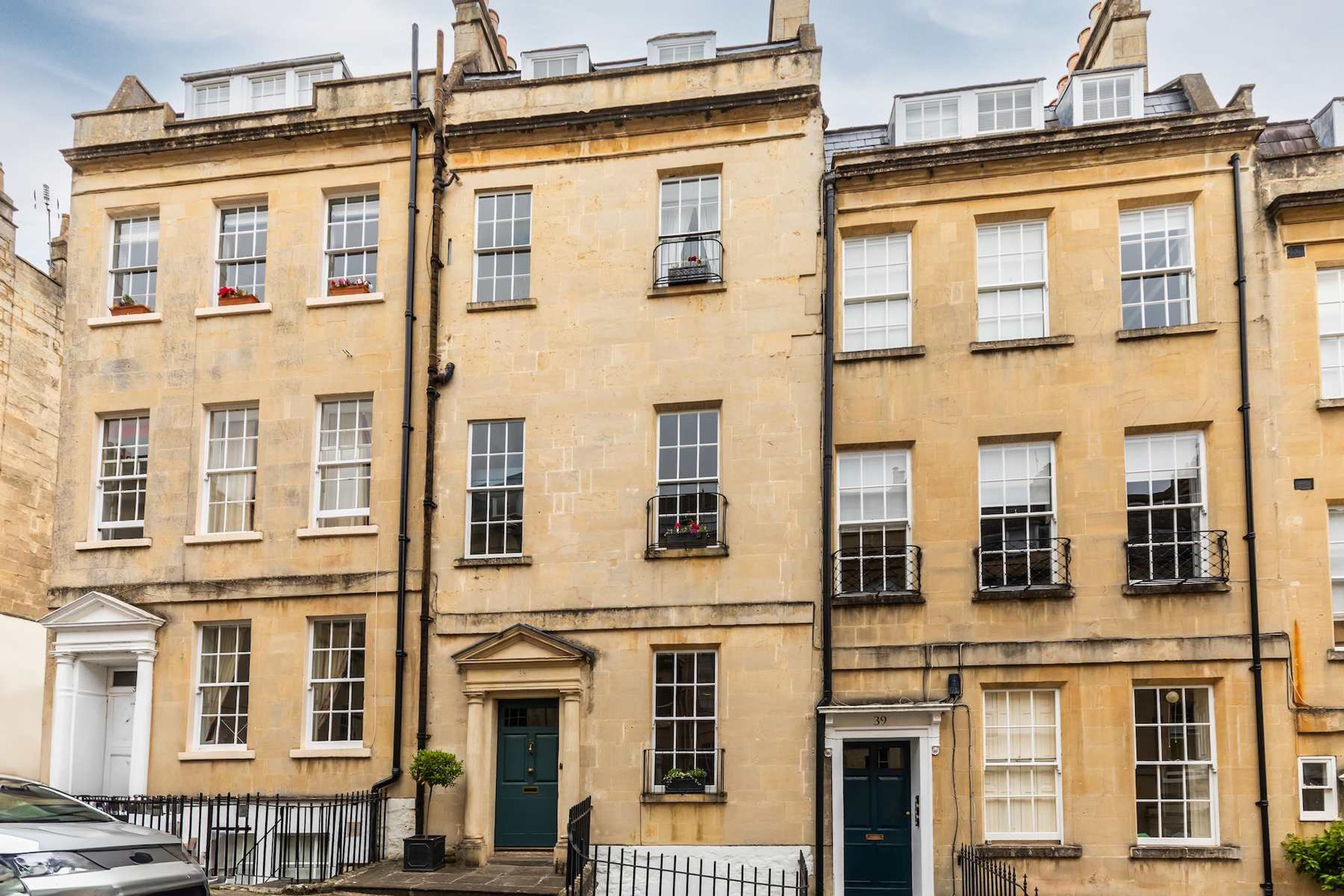 A row of traditional terraced houses with uniform architecture, featuring symmetrical windows and doors, and a consistent facade.