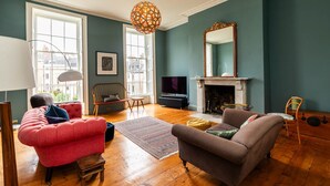 A living room with a fireplace, a large mirror, and a red sofa. - Grand Georgian Townhouse With Garden (Bath)