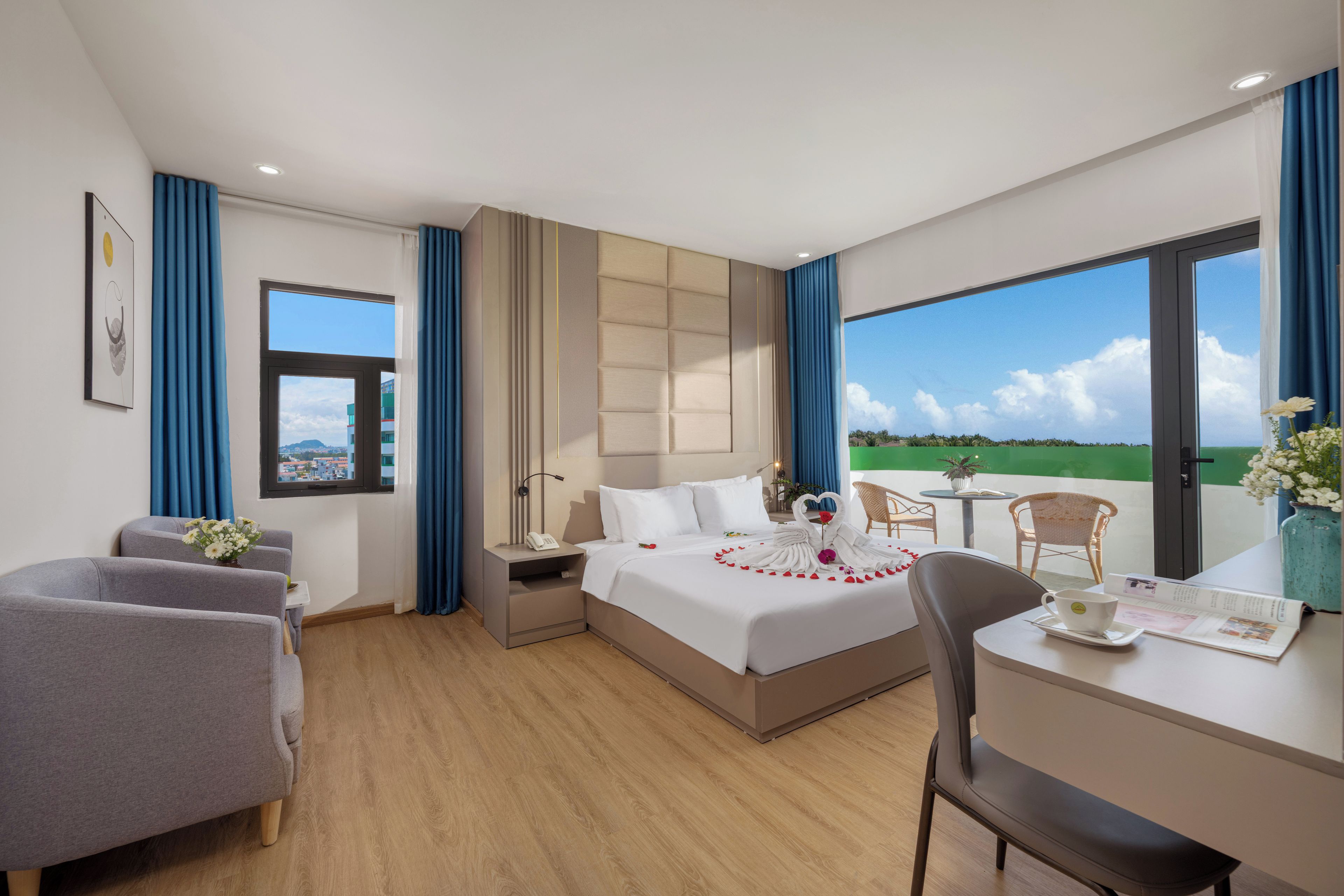 A hotel room with a bed, a desk, a chair, a small table, and a view of the outdoors.