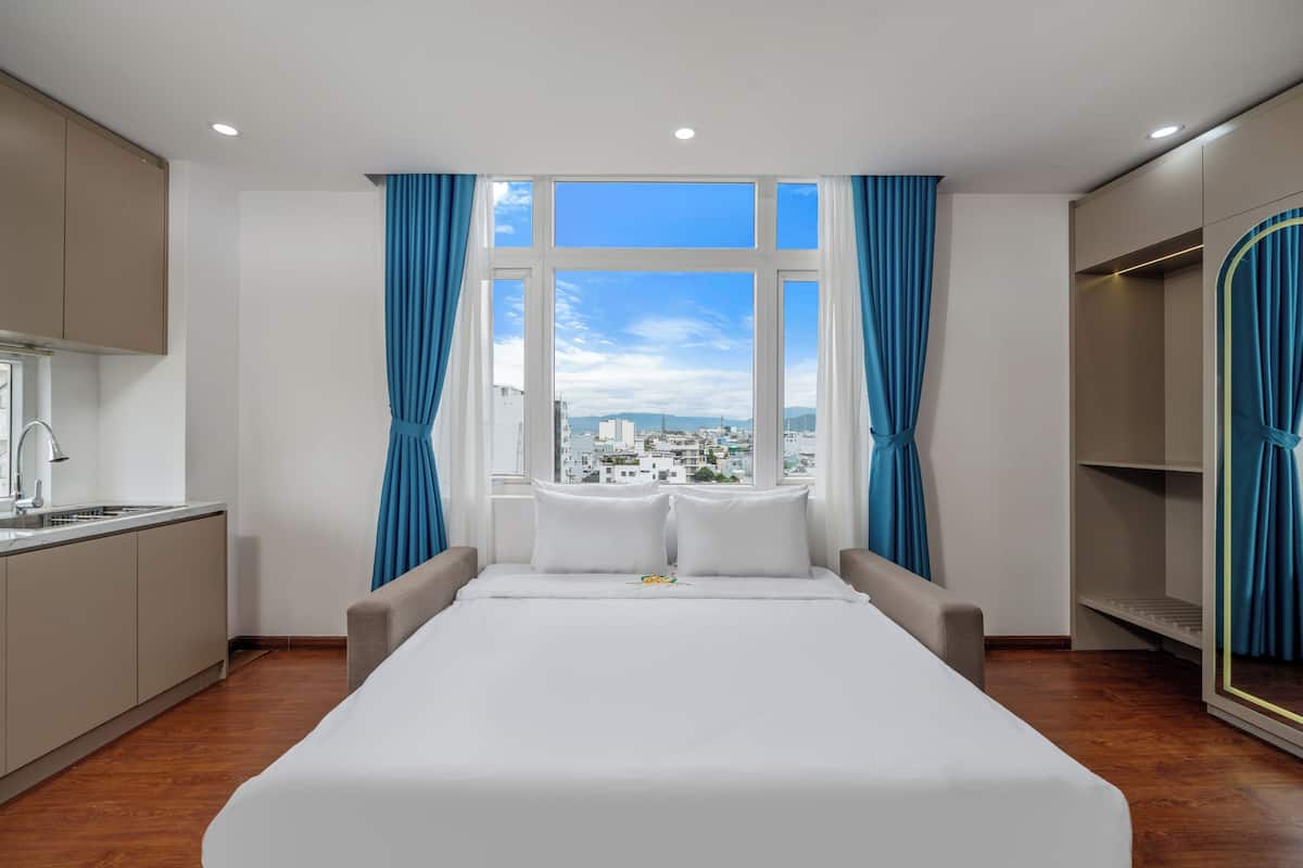 Una habitación de hotel con una cama grande, vistas a la ciudad, una kitchenette y un armario.