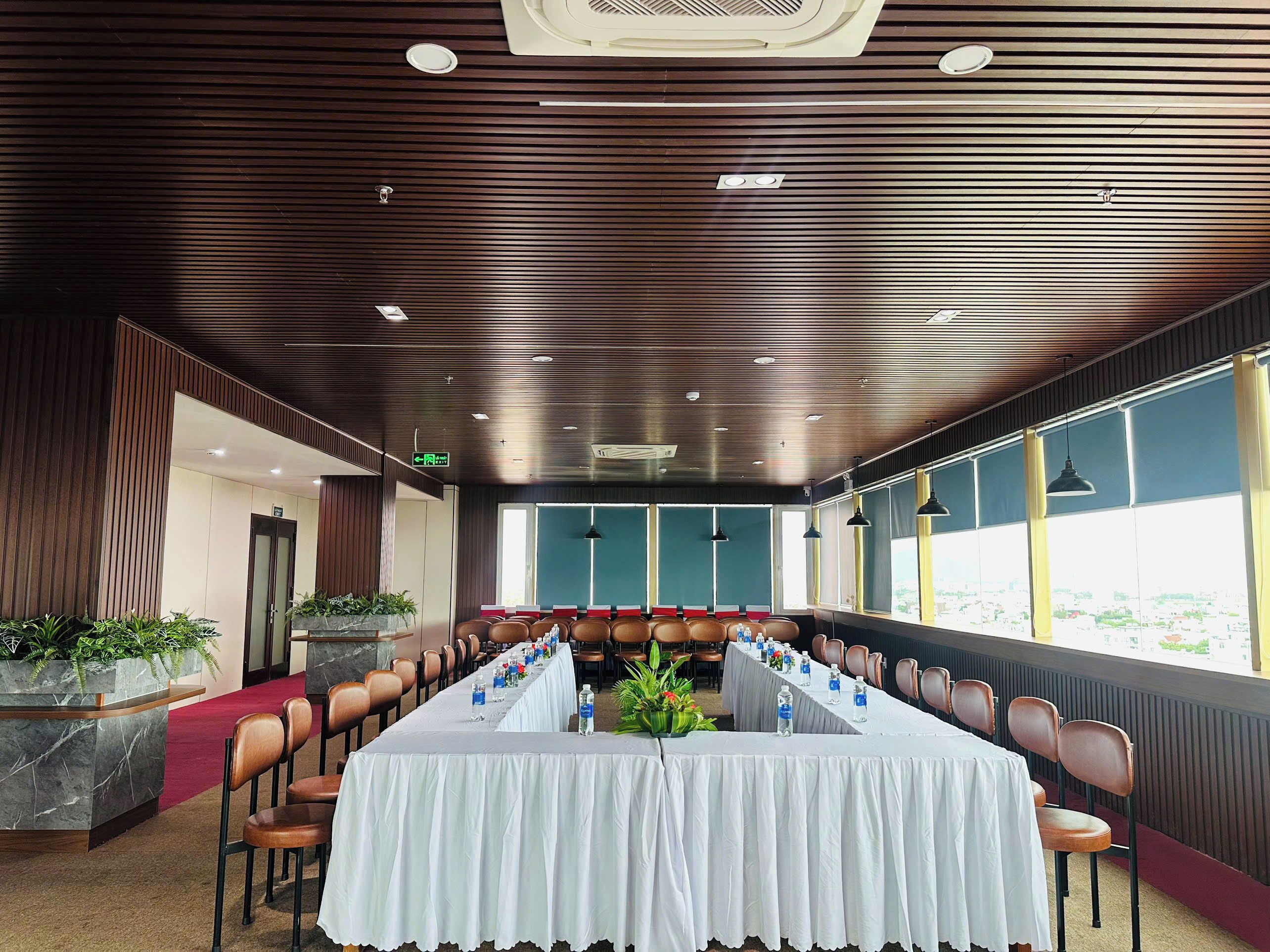 A conference room with a long table, chairs, and potted plants.