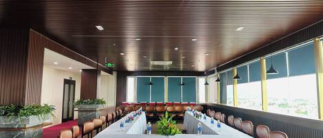 A conference room with a long table, chairs, and potted plants.